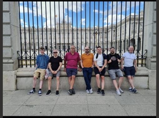 A group of men posing for a photo in front of a fence

Description automatically generated with medium confidence